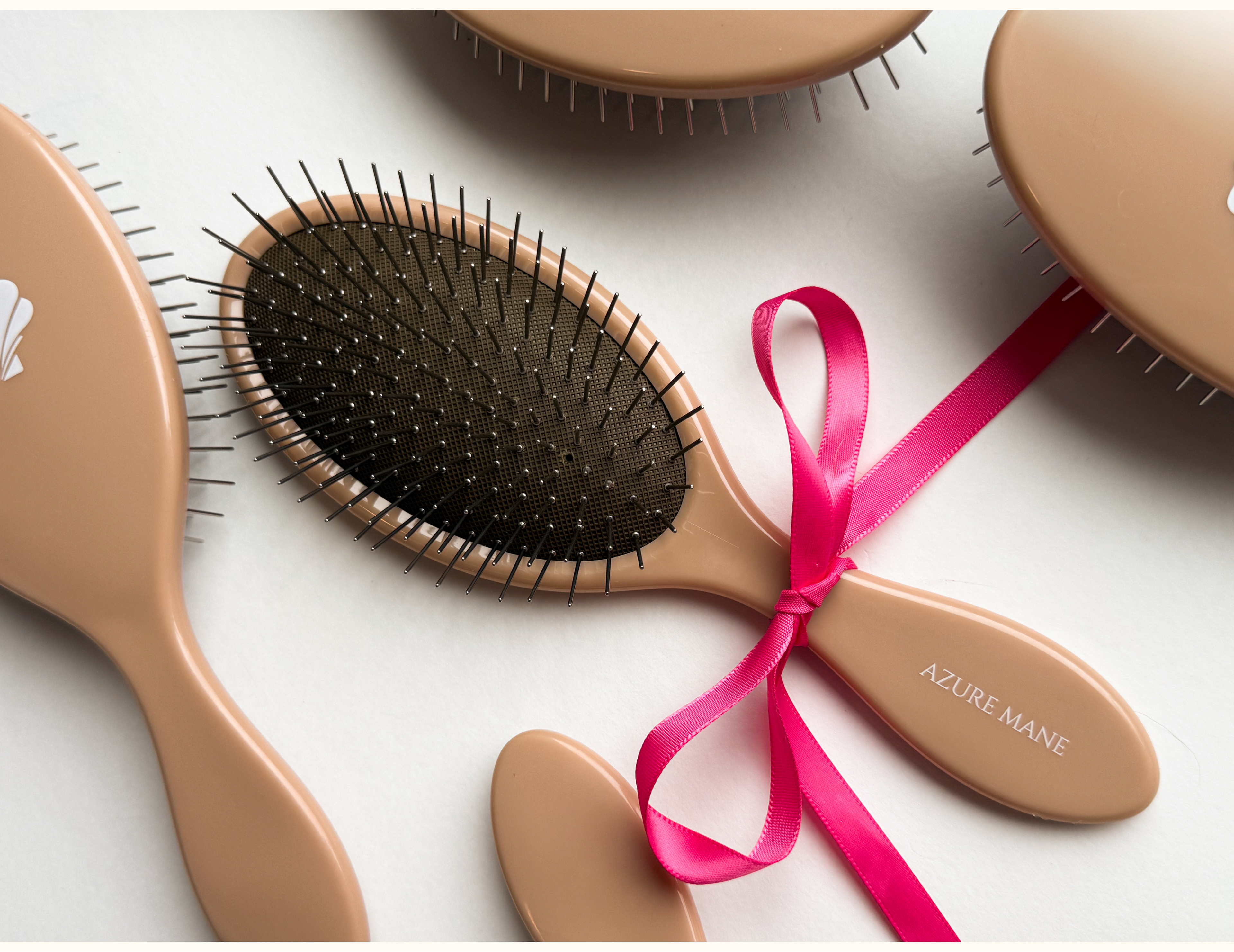 Set of hairbrushes with a pink ribbon on a light background